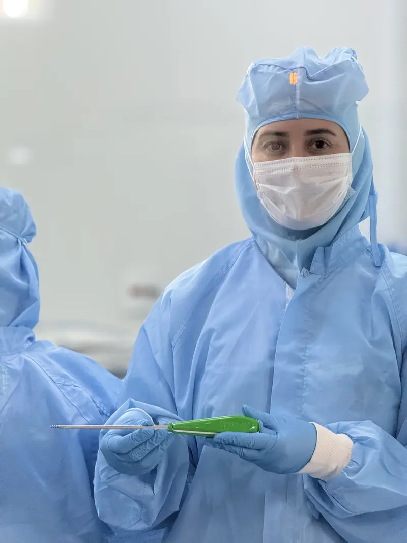 Sartori team member in the clean room holding a surgical instrument
